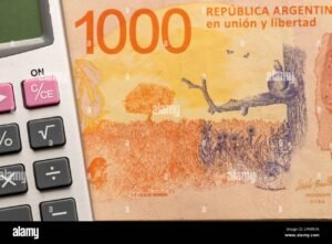 billete argentino junto a calculadora y monedas