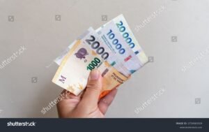 manos sosteniendo billetes y factura argentina