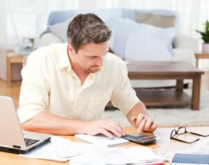 persona organizando finanzas con calculadora y laptop